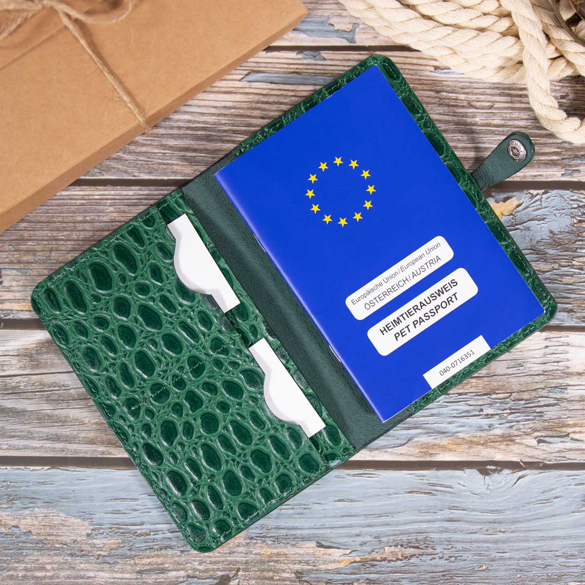 Befüllte grüne Kroko-Leder Heimtierausweishülle. Der großzügige Schnitt bietet komfortabel Platz für den blauen EU-Heimtierausweis, Visitenkarten und wichtige tierärztliche Dokumente.