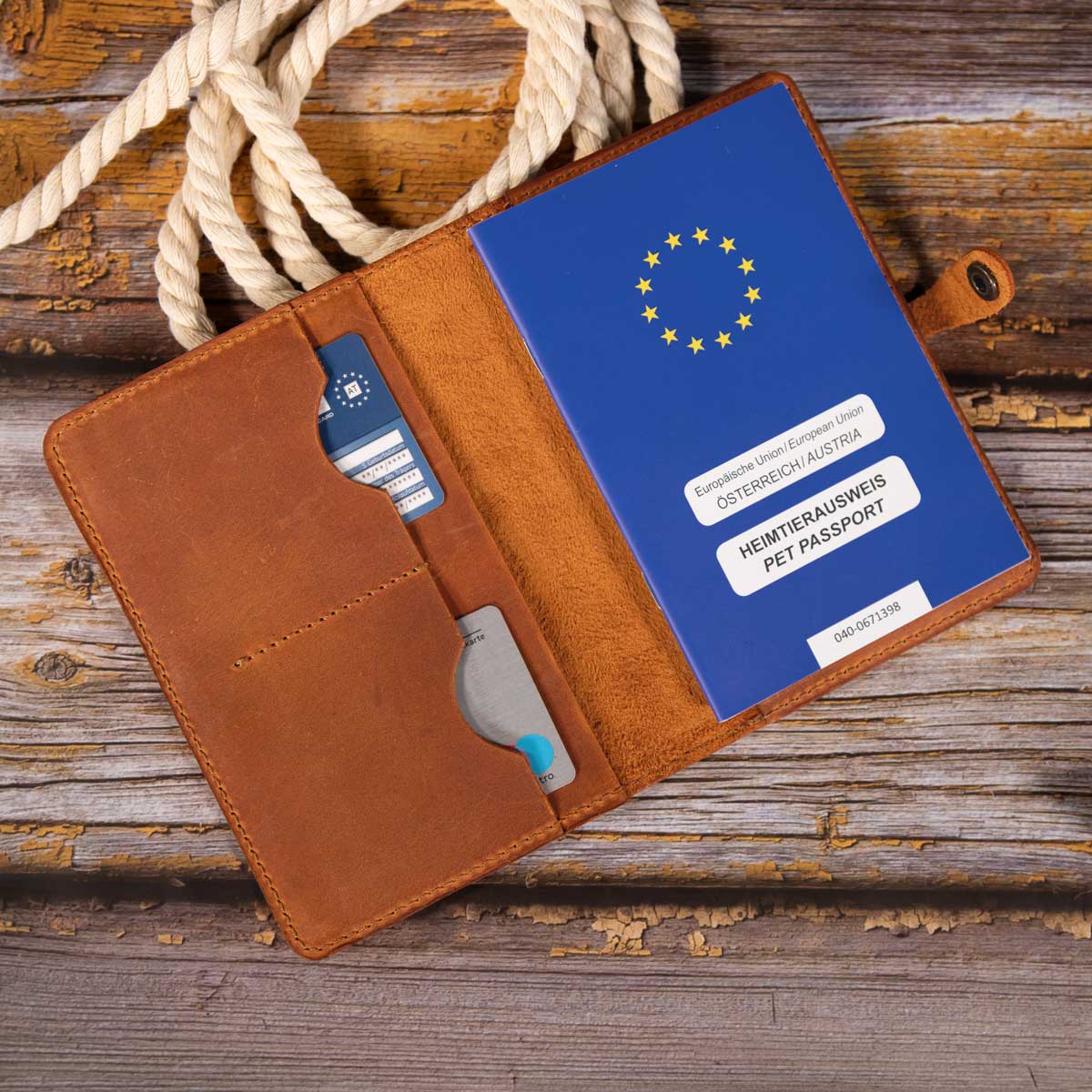 Geöffnete cognacfarbene Leder-Impfpasshülle, befüllt mit einem blauen EU-Heimtierausweis und Sicht auf die Kartenfächer.