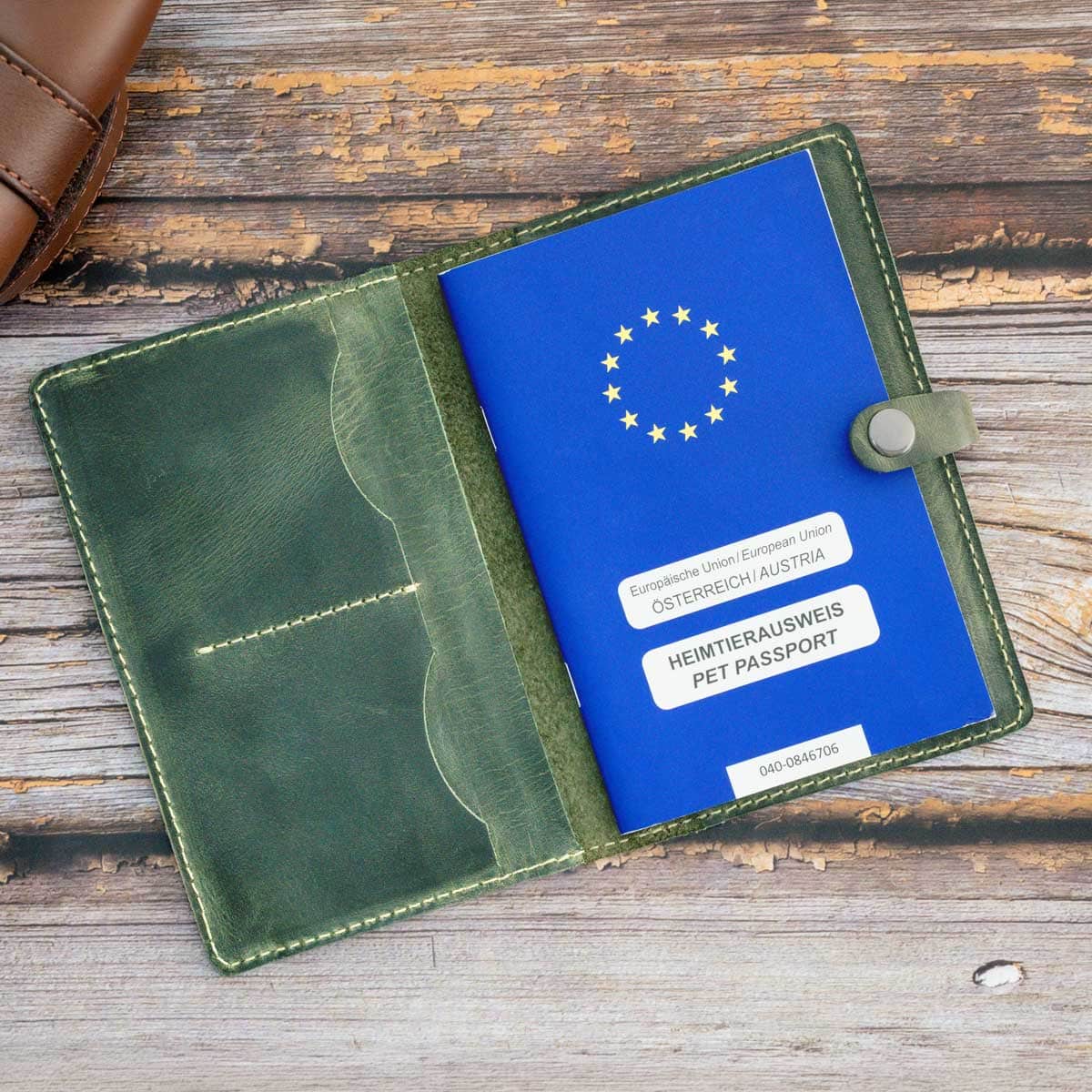 Geöffnete und befüllte Heimtierausweishülle aus Leder in Oliv mit einem eingelegten blauen EU-Heimtierausweis.