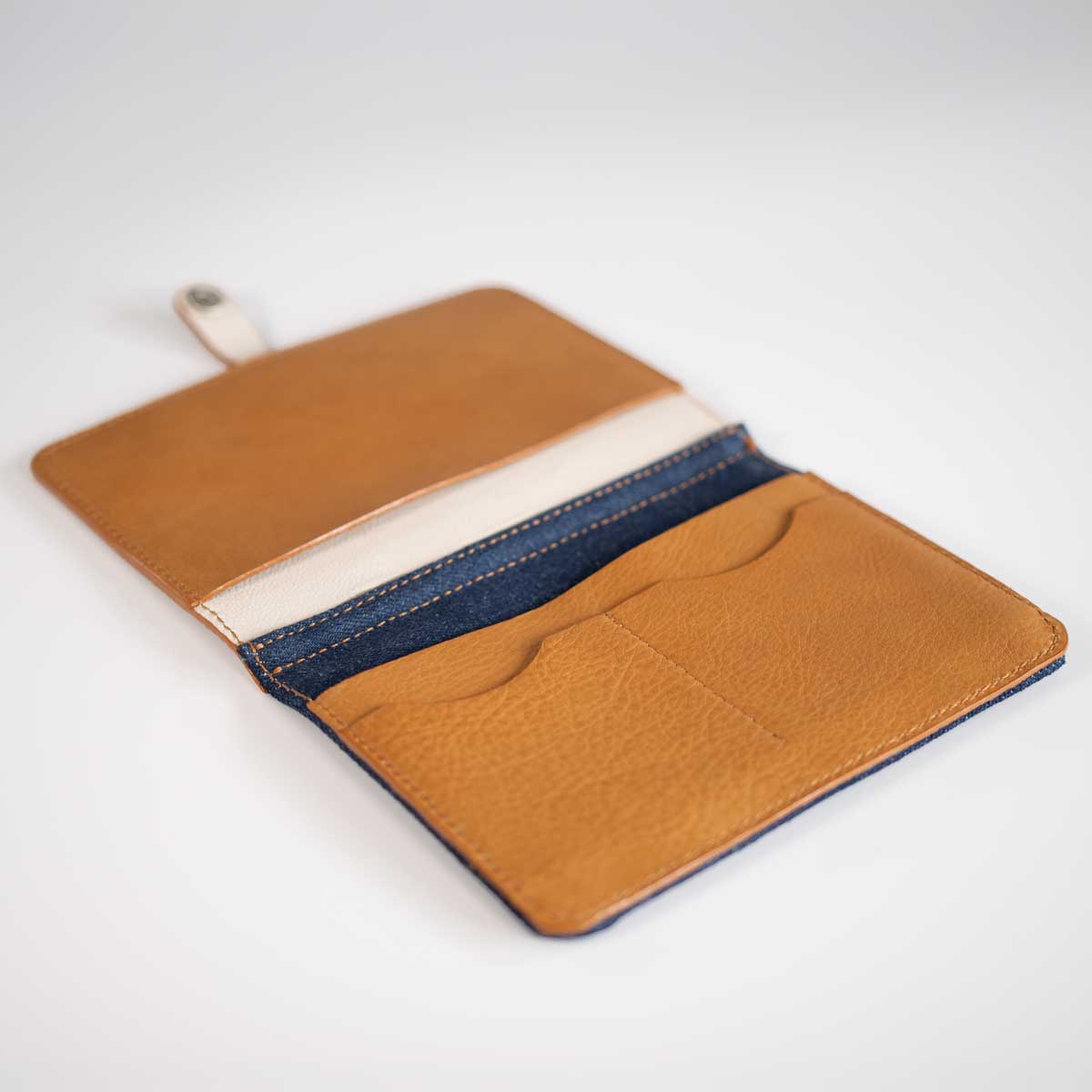 Innenansicht der leeren Kombi-Impfpasshülle mit cognacfarbenen Lederfächern und robust vernähtem Denim-Stoff.