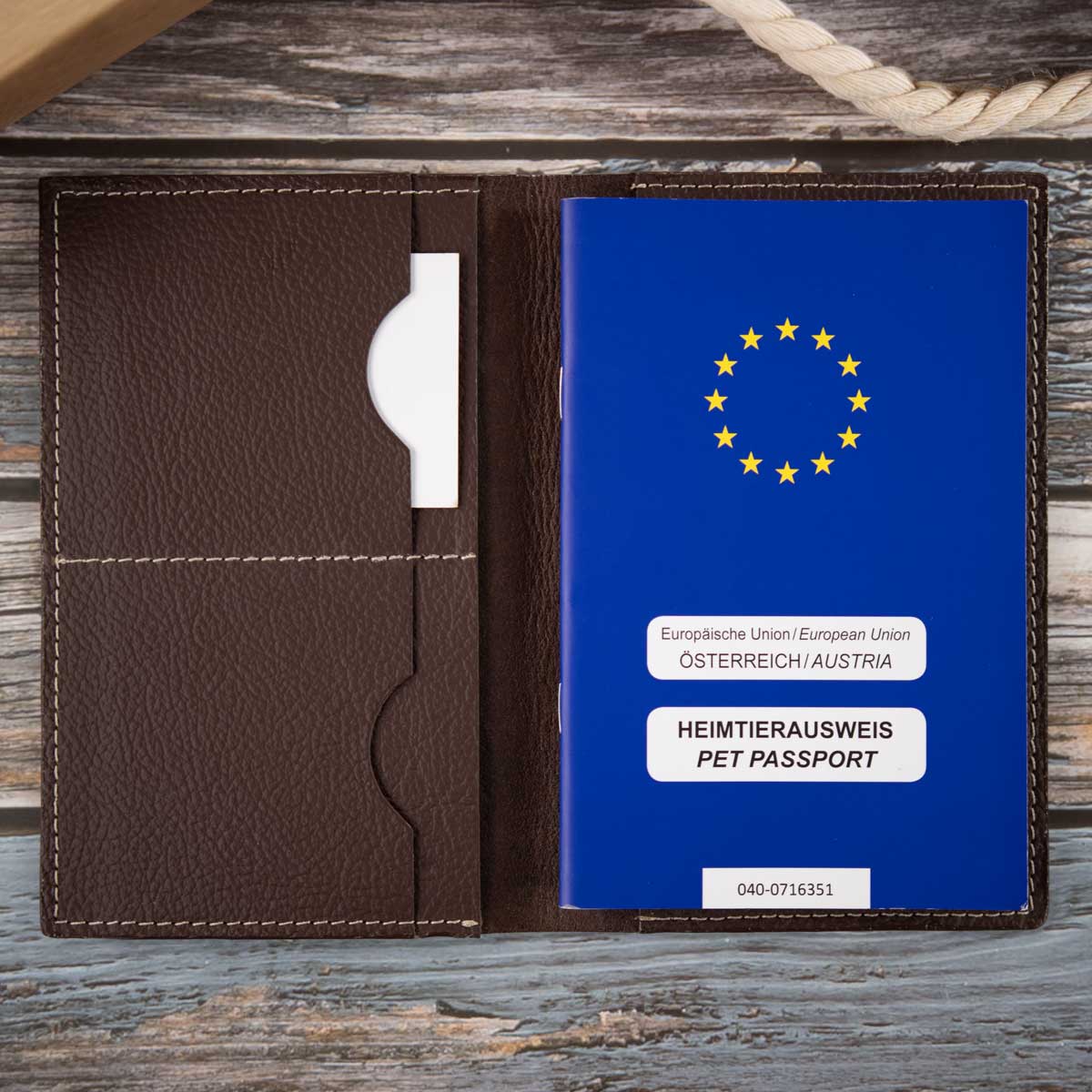 Geöffnete dunkelbraune Leder-Impfpasshülle, befüllt mit einem EU-Heimtierausweis und Sicht auf die präzise Fächeraufteilung