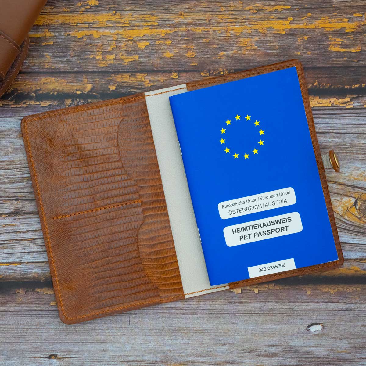 Geöffnete Heimtierausweishülle aus Leder, befüllt mit einem blauen EU-Heimtierausweis. Zusätzlicher Platz für Tierarztbefunde und Karten ist sichtbar