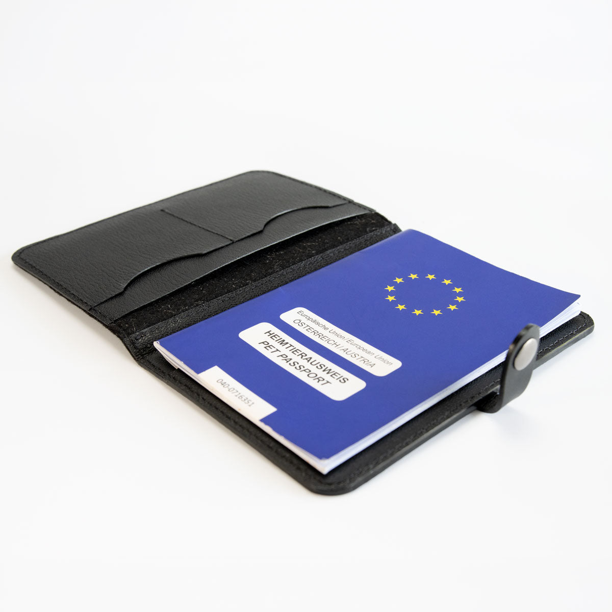 Geöffnete schwarze Heimtierausweishülle aus Leder und Filz, befüllt mit einem blauen EU-Heimtierausweis und Sicht auf die praktische Aufteilung.