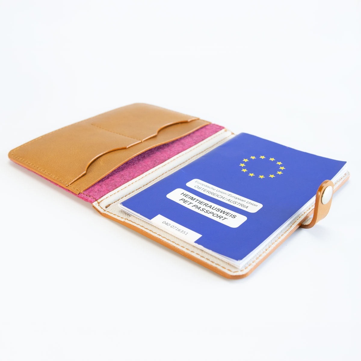 Geöffnete Impfpasshülle aus Leder und Filz in Cognac und Pink, befüllt mit einem blauen EU-Heimtierausweis und Sicht auf die praktische Aufteilung.