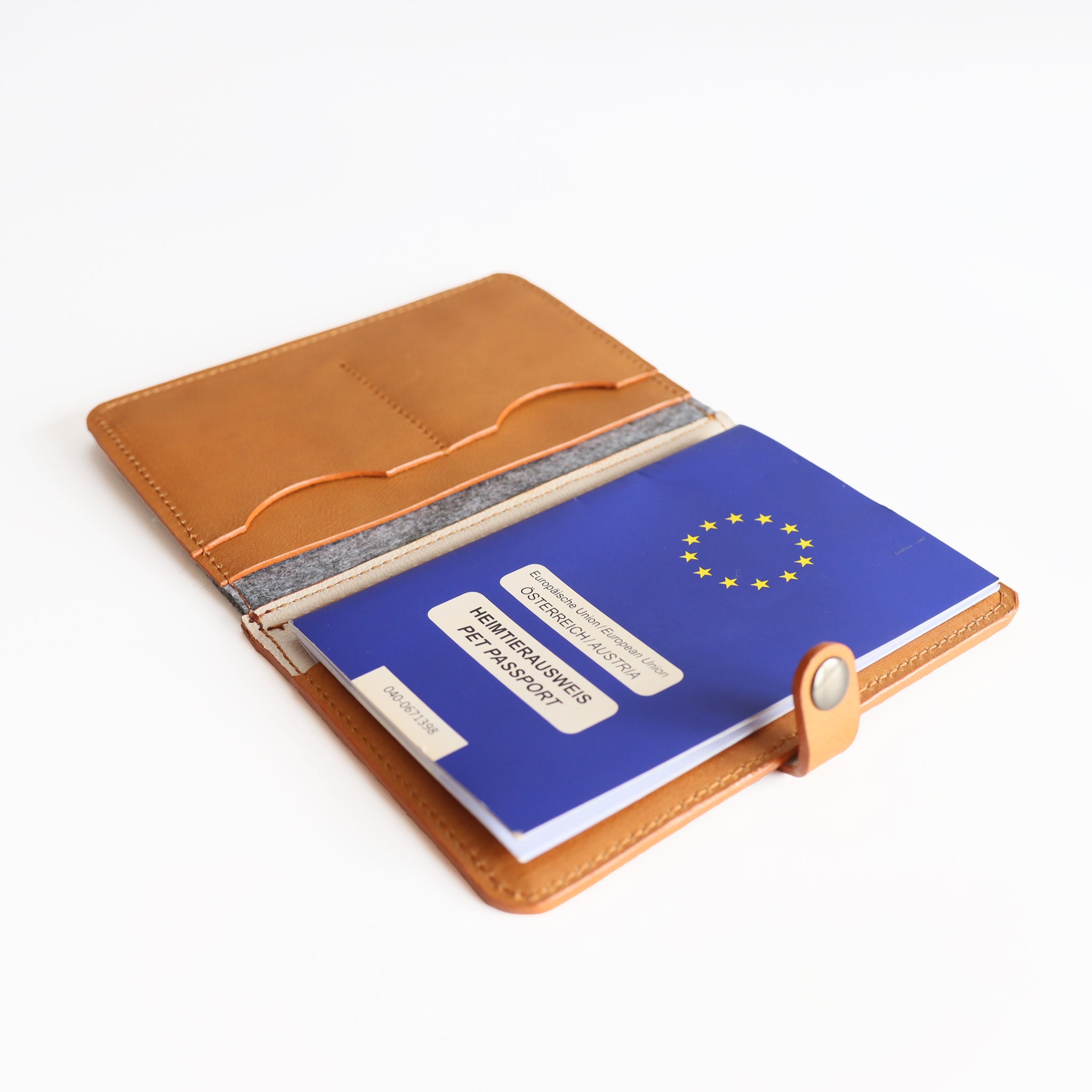 die Heimtierasuweishuelle liegt offen auf einem Studiountergrund und man sieht den EU-Heimtierausweis wie er in diese Hülle eingeschoben wurde