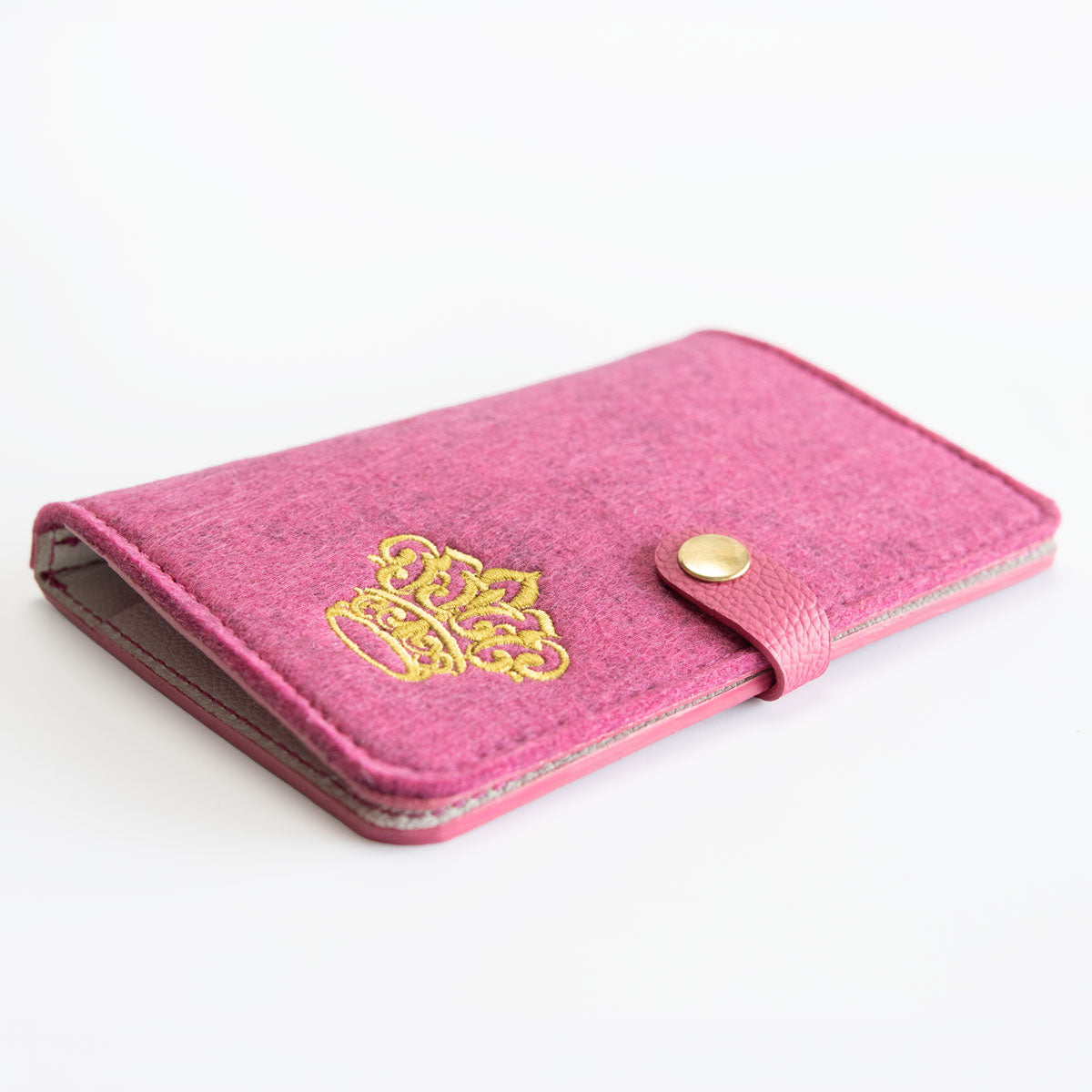 Vorderseite der geschlossenen Heimtierausweishülle in leuchtendem Pink mit einem präzisen Kronen-Stick und goldenem Druckknopf.