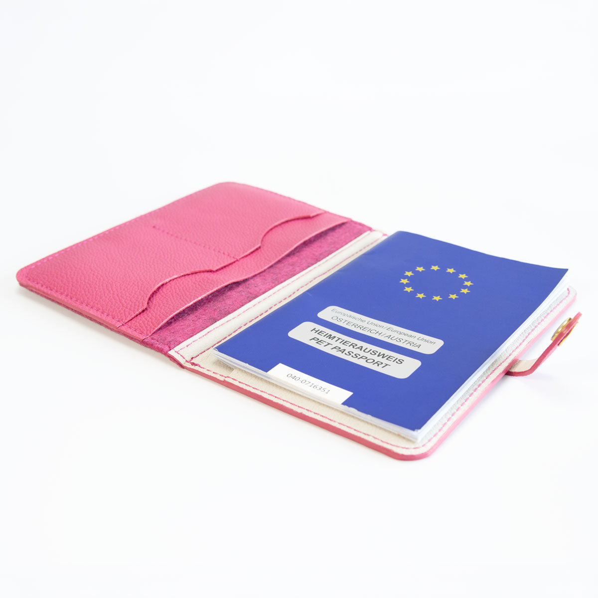 Geöffnete pinke Leder-Filz-Impfpasshülle, befüllt mit einem blauen EU-Heimtierausweis und Sicht auf die Fächeraufteilung.