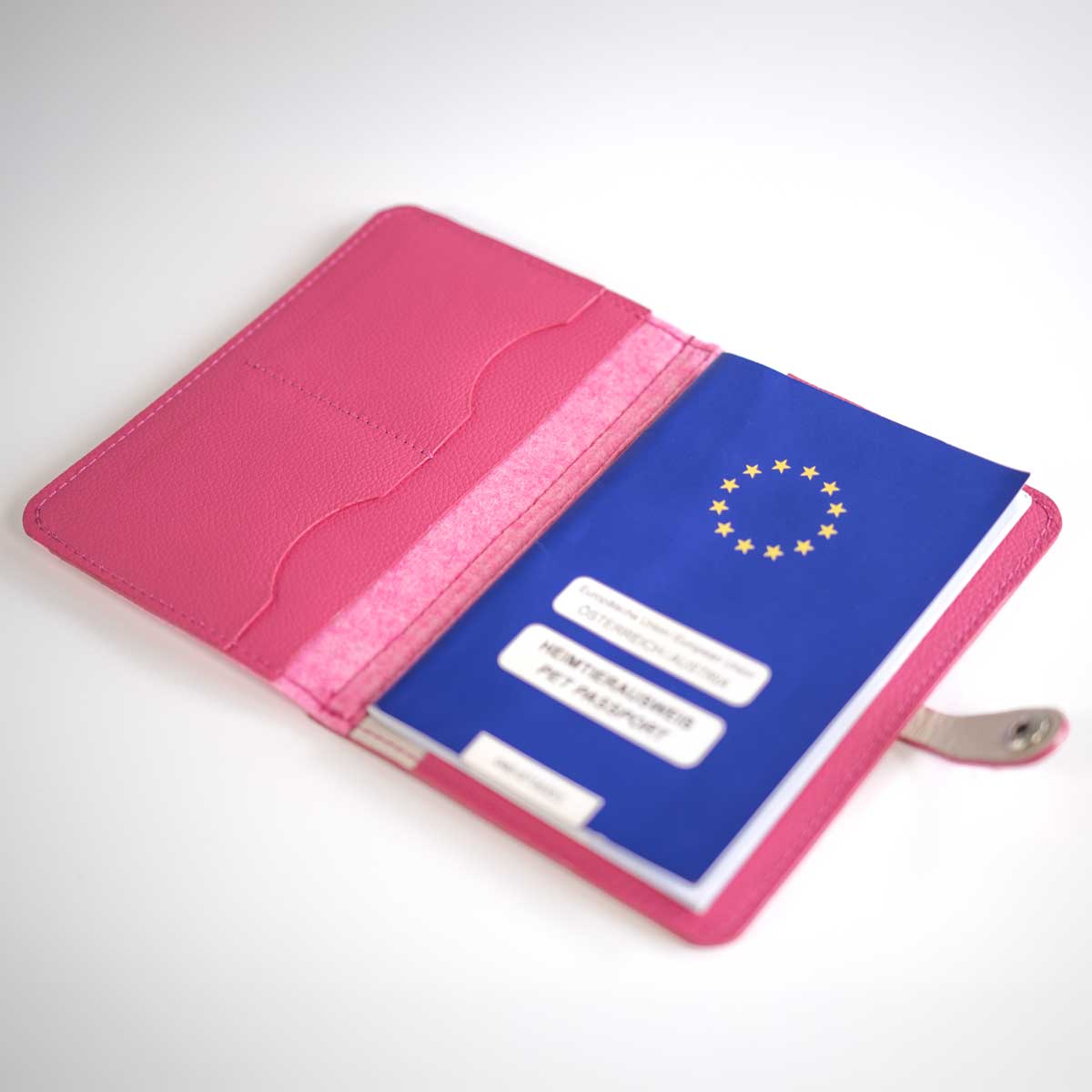 Geöffnete Heimtierausweishülle in Pink und Rosa-Melange, befüllt mit einem blauen EU-Heimtierausweis und Sicht auf die Kartenfächer.