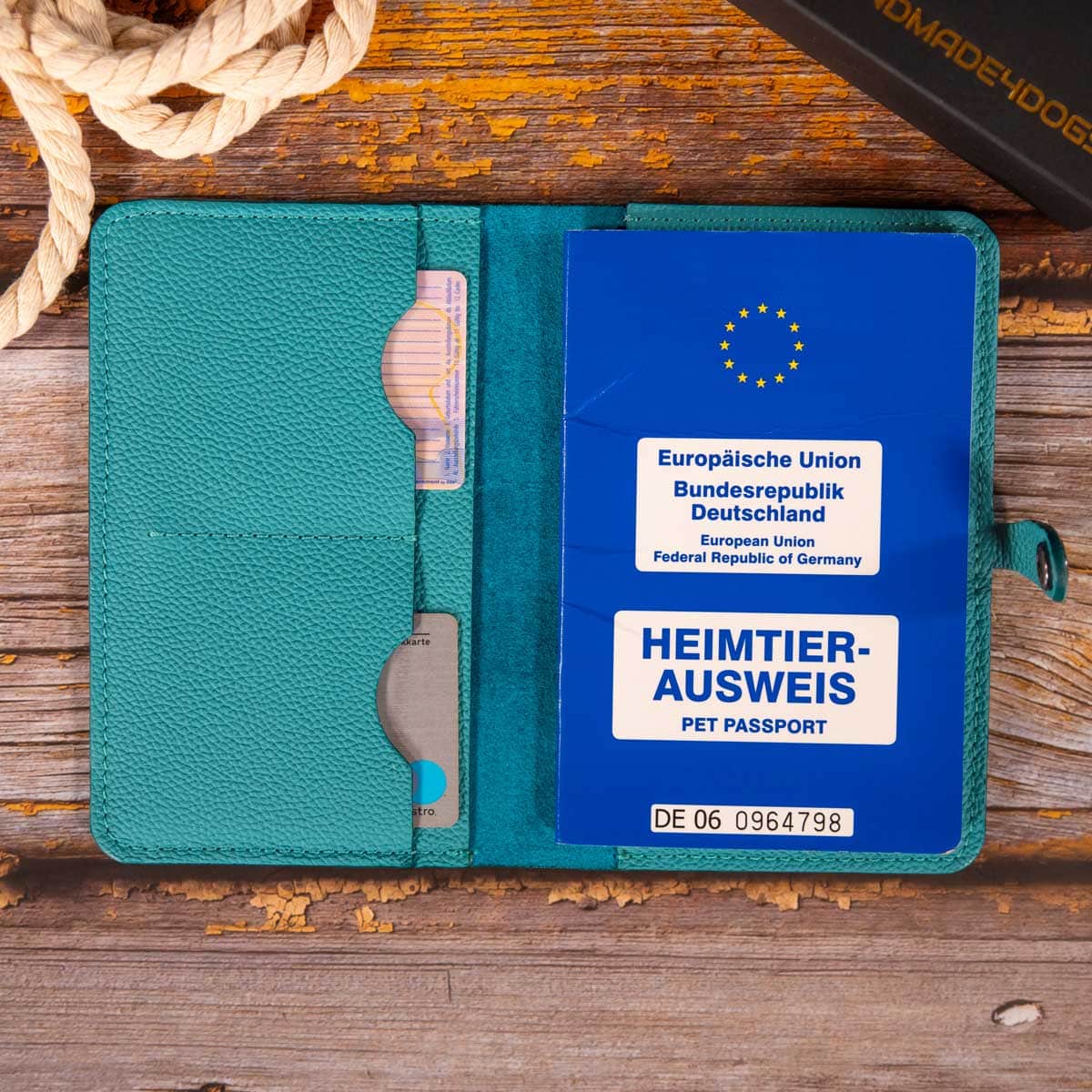 Geöffnete türkisfarbene Leder-Impfpasshülle, befüllt mit einem EU-Heimtierausweis und Sicht auf die praktischen Kartenfächer.