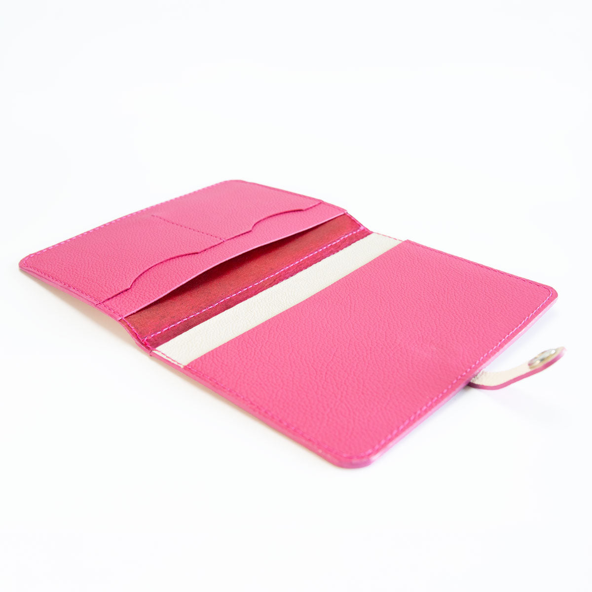 Innenansicht der leeren Lederhülle in Pink und Off-White mit passgenauen Kartenfächern und großen Einschubfächern.
