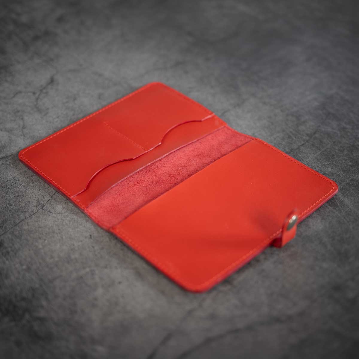 Geöffnete, ungefütterte Leder-Impfpasshülle in Signalrot, die die abgenähten Kartenfächer und die großen Einschubfächer für Ausweise zeigt.