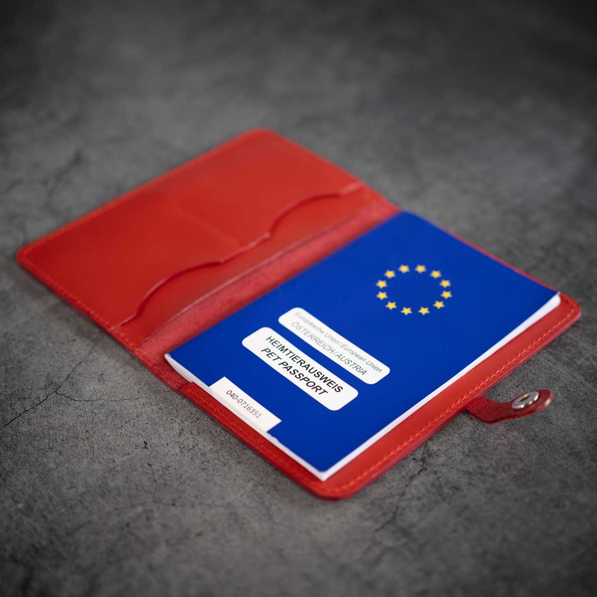 Schräge Innenansicht der signalroten Lederhülle, befüllt mit einem blauen EU-Heimtierausweis und Platz für zusätzliche Tierarzt-Dokumente.