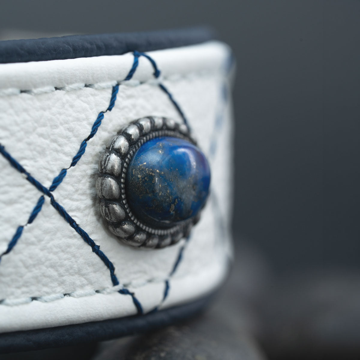 Nahaufnahme eines echten Lapislazuli-Cabochons in silberfarbener Fassung auf weißem Rindsnappa