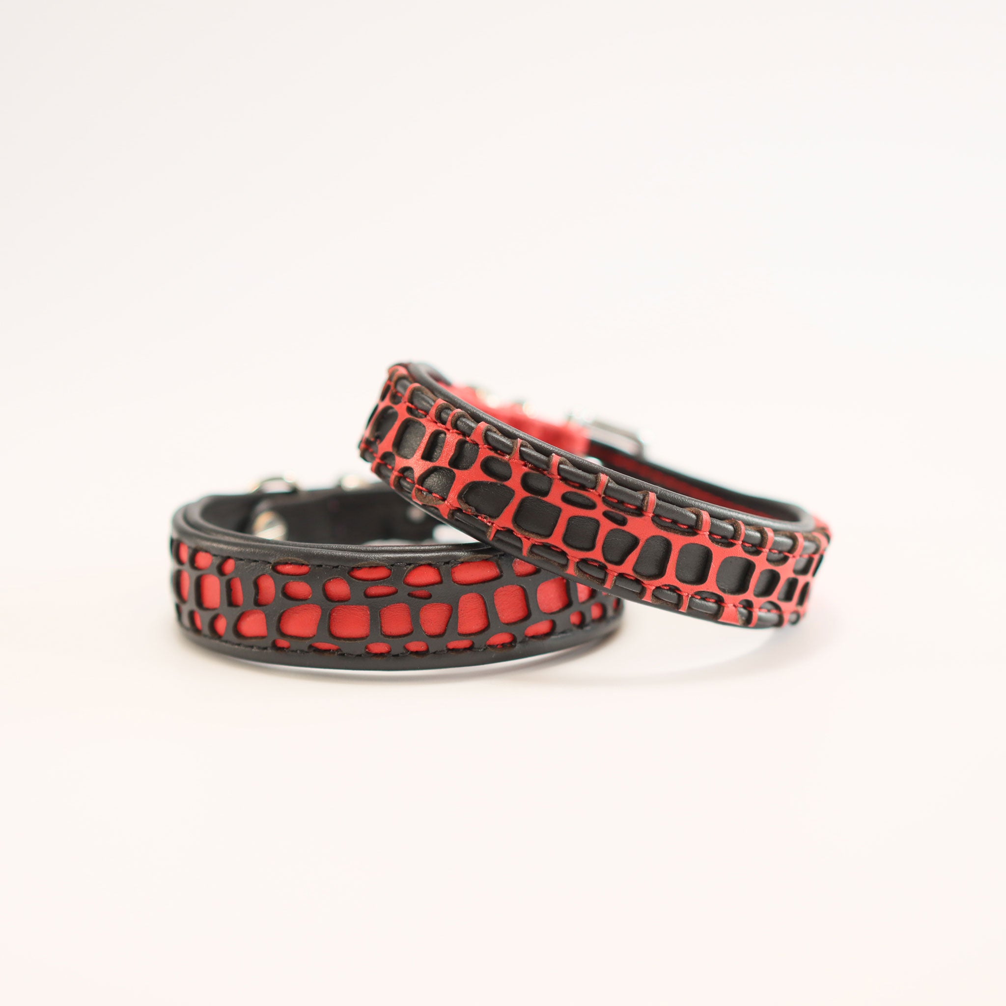 Zwei handgefertigte Lederhalsbänder in Rot und Schwarz mit laser-geschnittenem Krokodil-Muster.