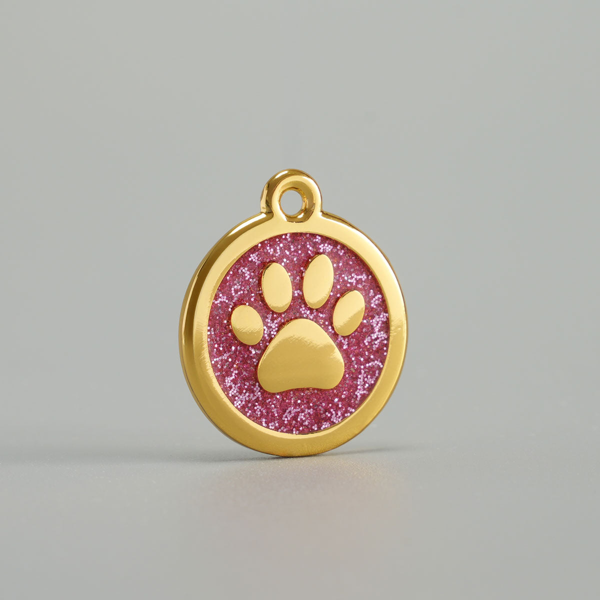 Goldene Hundemarke mit erhabener Pfote und rosa Glitzer-Epoxidharz-Hintergrund
