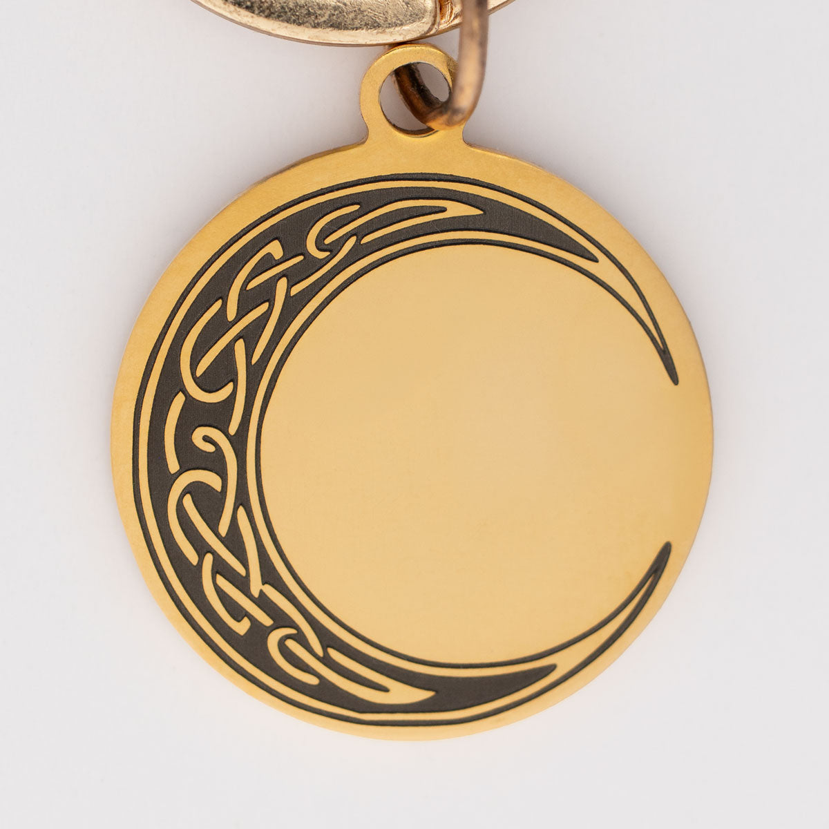 eine goldene Edelstahl Hundemarke mit einem gravierten keltischen Mond
