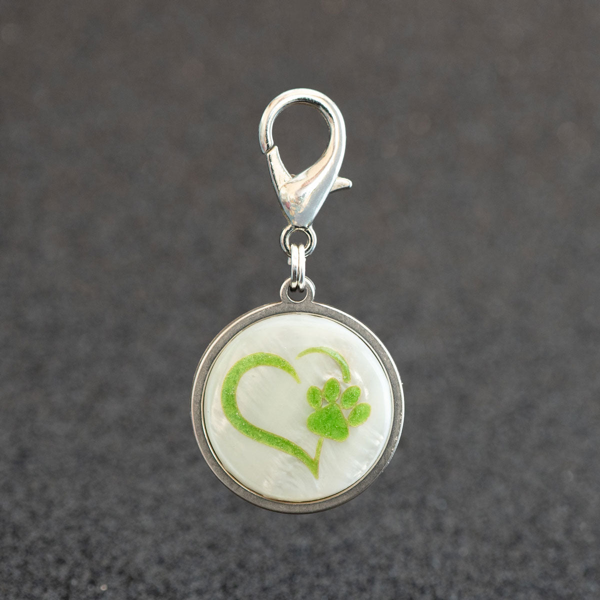 Personalisierte silberne Hundemarke mit Herz-Pfote-Motiv auf einer echten weißen Muschelplatte