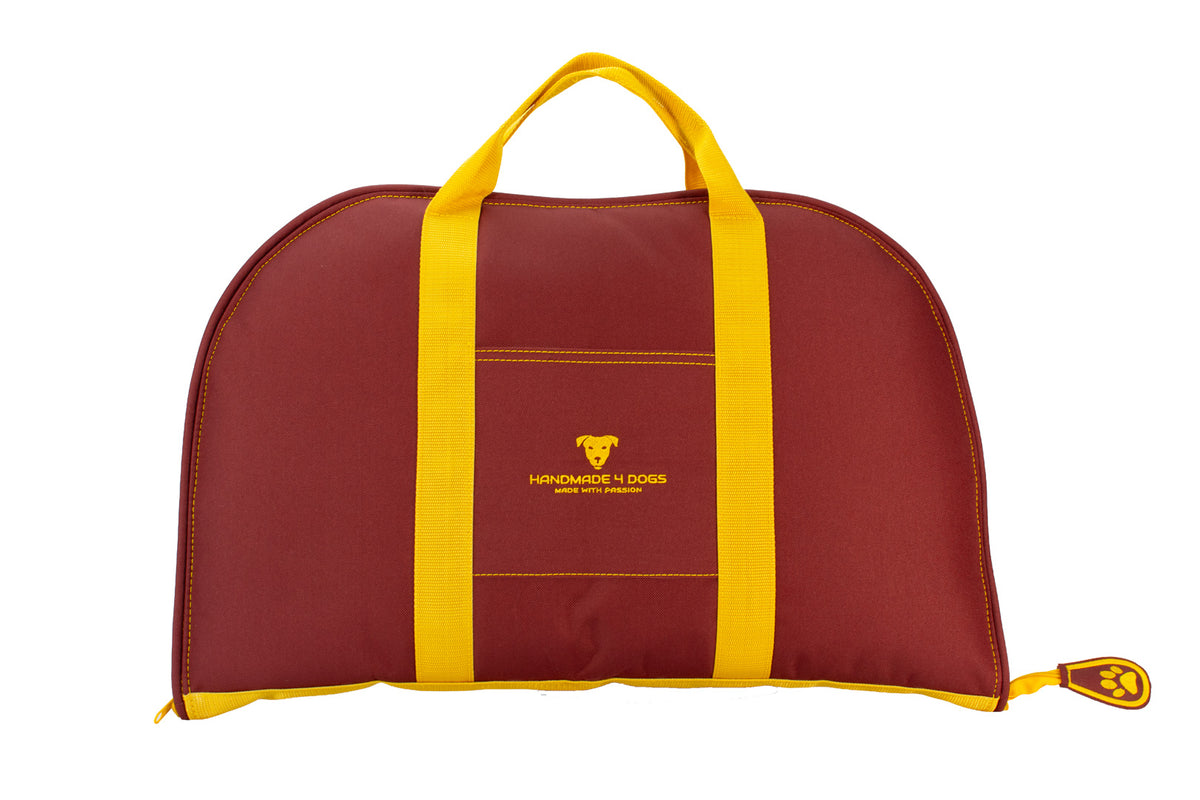 Vorderansicht des bordeauxroten Dog Bed To Go mit gelben Ziernähten, sonnengelben Tragegurten und gesticktem handmade4dogs Logo.