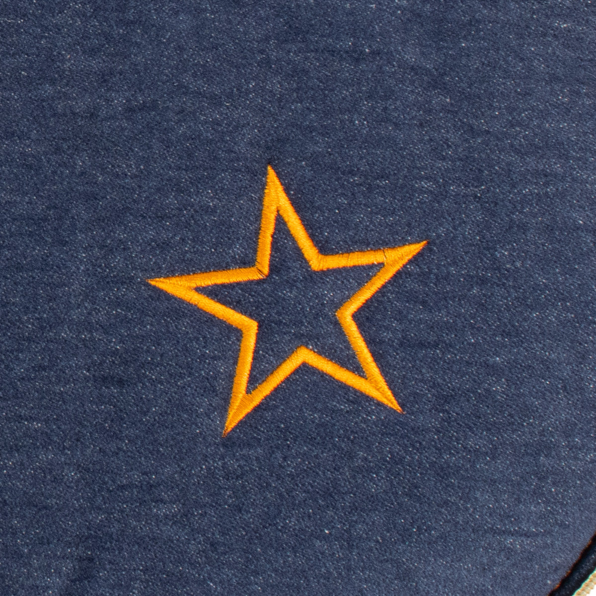 Detailaufnahme einer orangefarbenen Sternenstickerei auf dunkelblauem Denim des handgefertigten Dog Bed To Go Hundereisebetts.