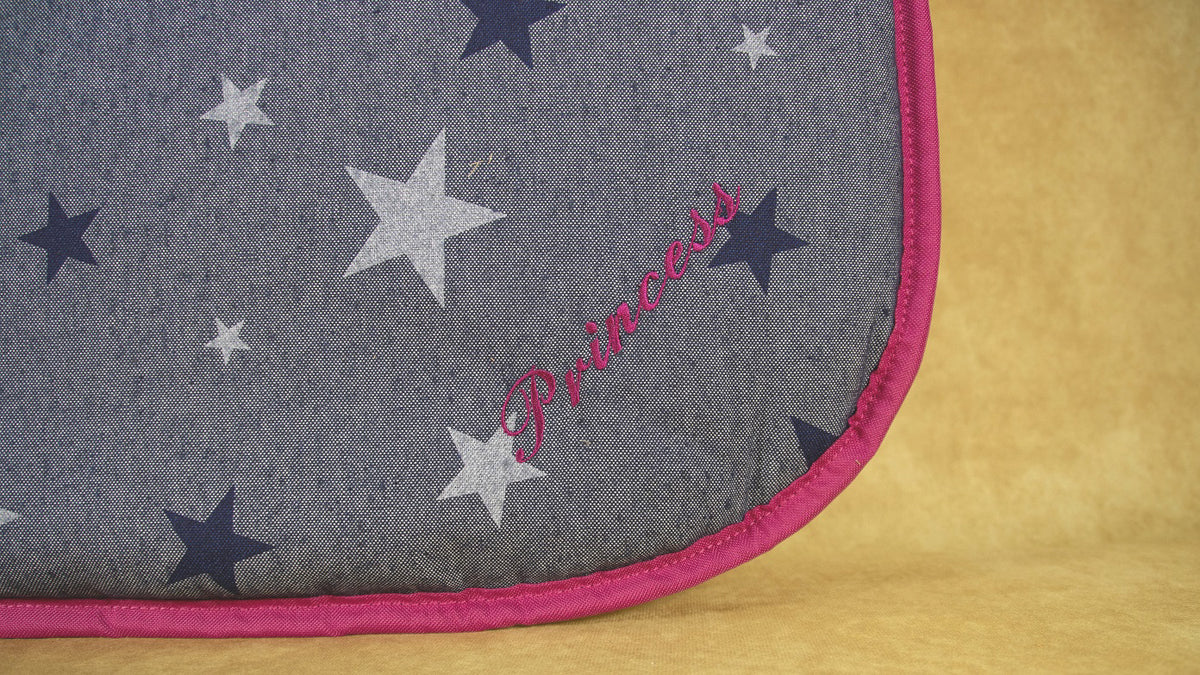 Detailaufnahme des Dog Bed To Go LIGHT mit jeansblauem Sternendekor, pinker Einfassung und Namensstickerei in Pink.