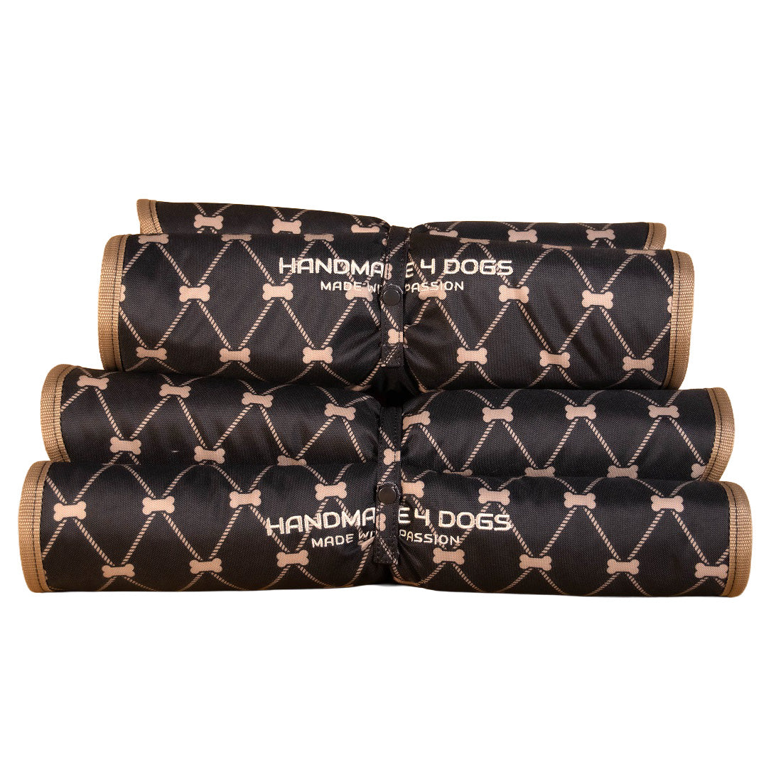 Gerolltes Dog Bed To Go LIGHT Hundereisebett mit schwarz-beigem Knochenprint und handmade4dogs Logo.