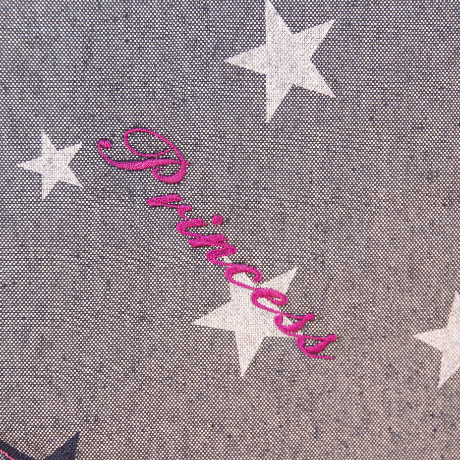 1. Detailaufnahme der pinken Stickerei „Princess“ auf der jeansfarbenen Liegefläche mit Sternendekor.