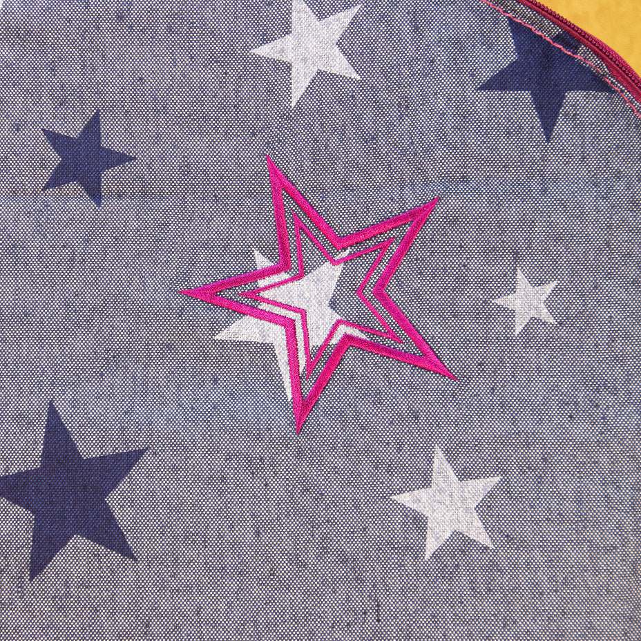 Detailaufnahme der pinken Sternstickerei auf der jeansfarbenen Liegefläche des Hundereisebetts Dog Bed To Go.