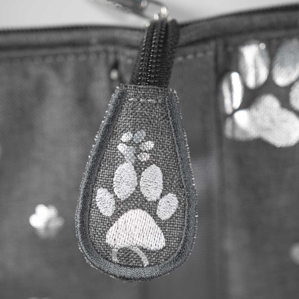 Detail des schwarzen Reißverschlusses mit bestickter Lasche im Pfotenmotiv