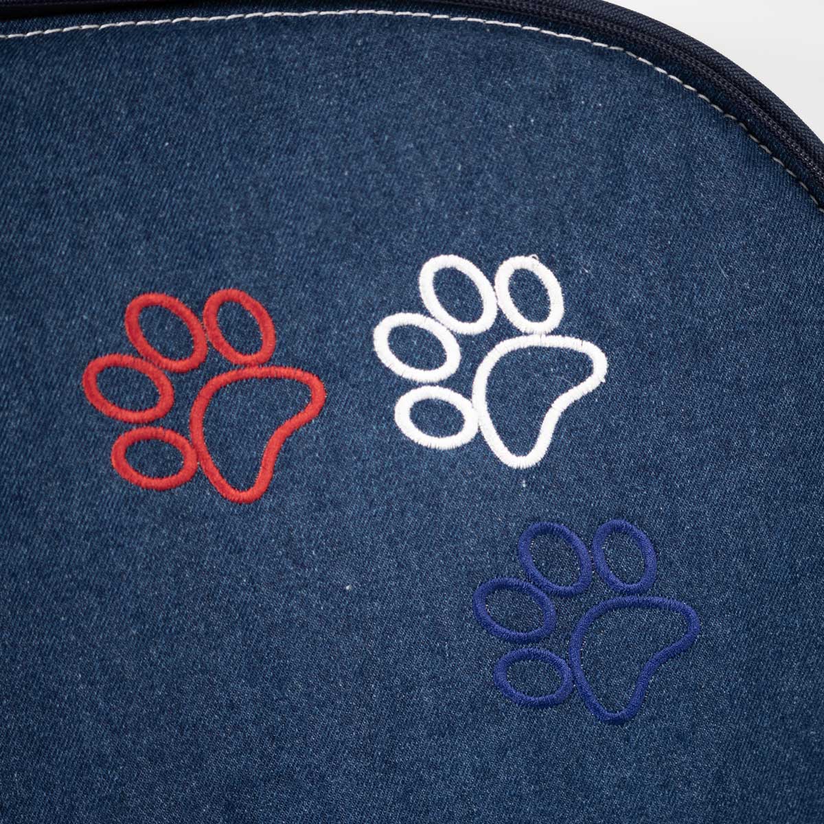 Detailansicht der Pfotenstickerei in Tricolore auf der Jeans-Liegefläche