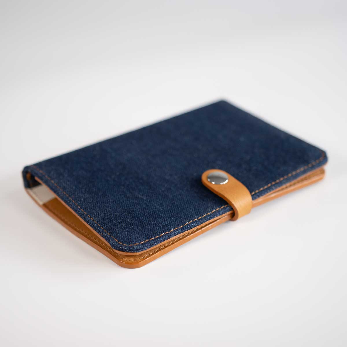 Schräge Ansicht der handgefertigten Leder-Denim-Hülle, die die hochwertige Verarbeitung und den doppellagigen Jeansstoff zeigt.