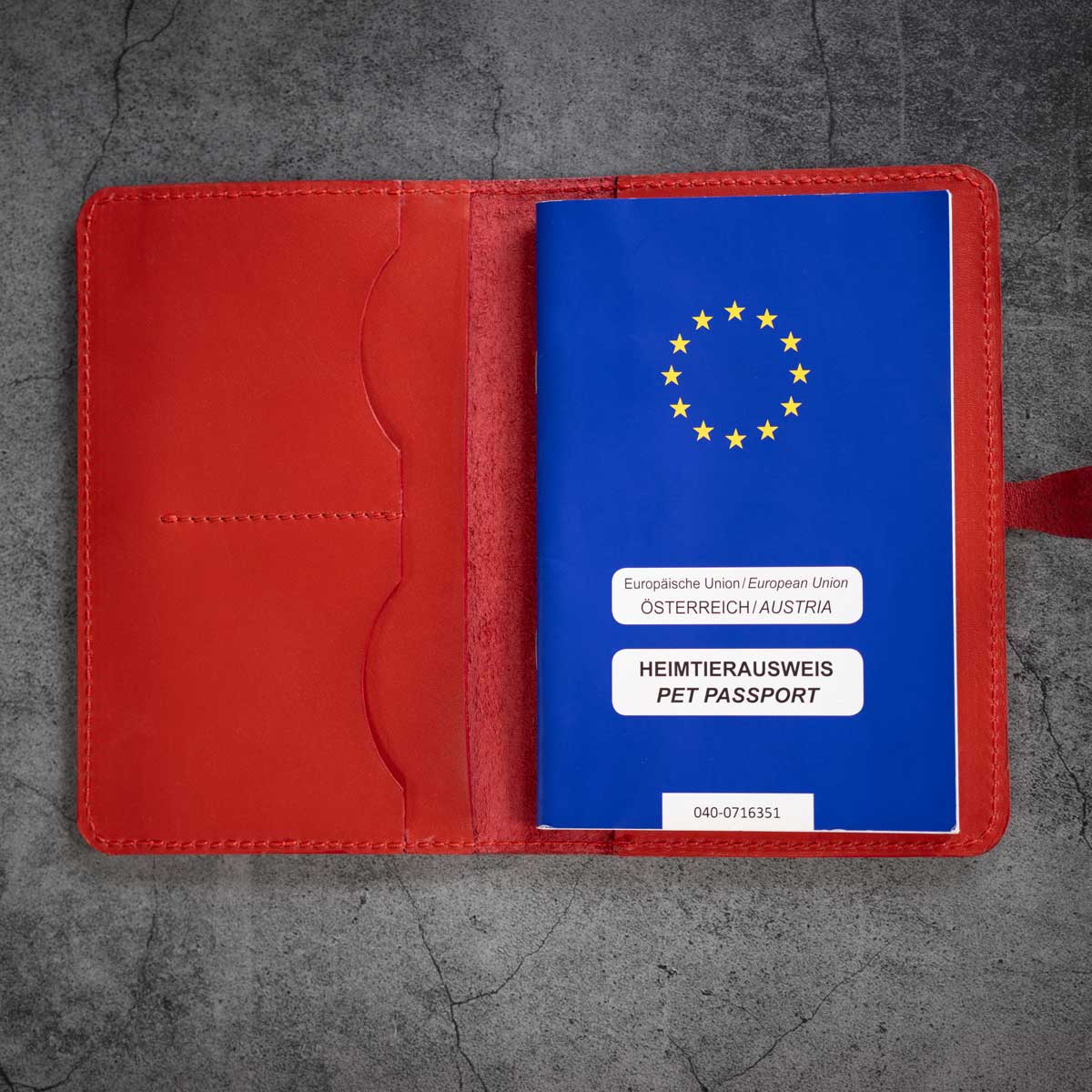 Draufsicht auf die geöffnete rote Heimtierausweishülle mit einem eingesteckten EU-Heimtierausweis auf der rechten Seite.