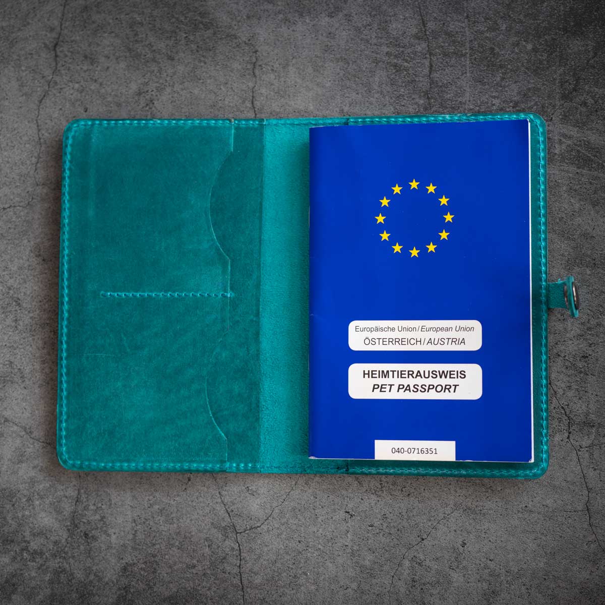 Detailaufnahme der geöffneten und befüllten Heimtierausweishülle aus Leder in Türkis mit Platz für Tierarztbefunde und Impfpass.