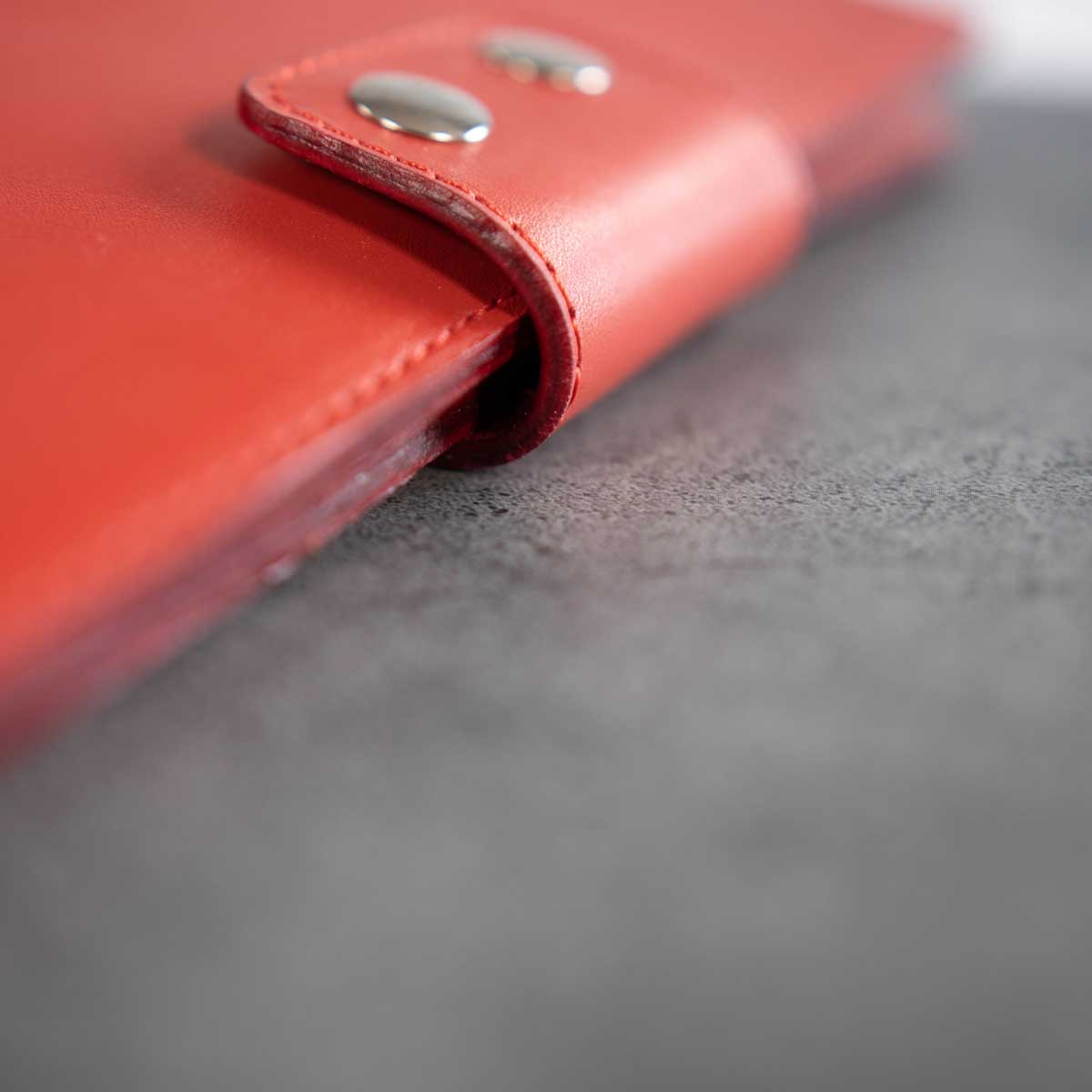 Detailaufnahme der aufwendig von Hand lackierten und gummierten Lederkanten des signalroten Travel Wallets. Höchste Handwerkskunst aus Österreich.