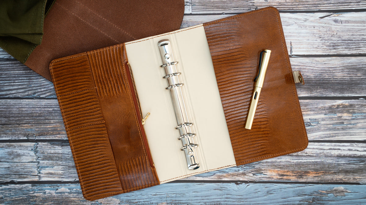 Geöffnetes A5-Leder-Ringbuch in Cognac und Off-White mit sechs Ringen, Reißverschlussfach und zwei Kartenfächern.