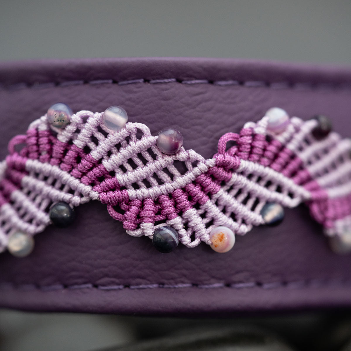 Nahaufnahme der blattähnlichen Micro-Makramee-Knoten in Flieder und Violett mit Amethyst-Perlen auf violettem Leder.