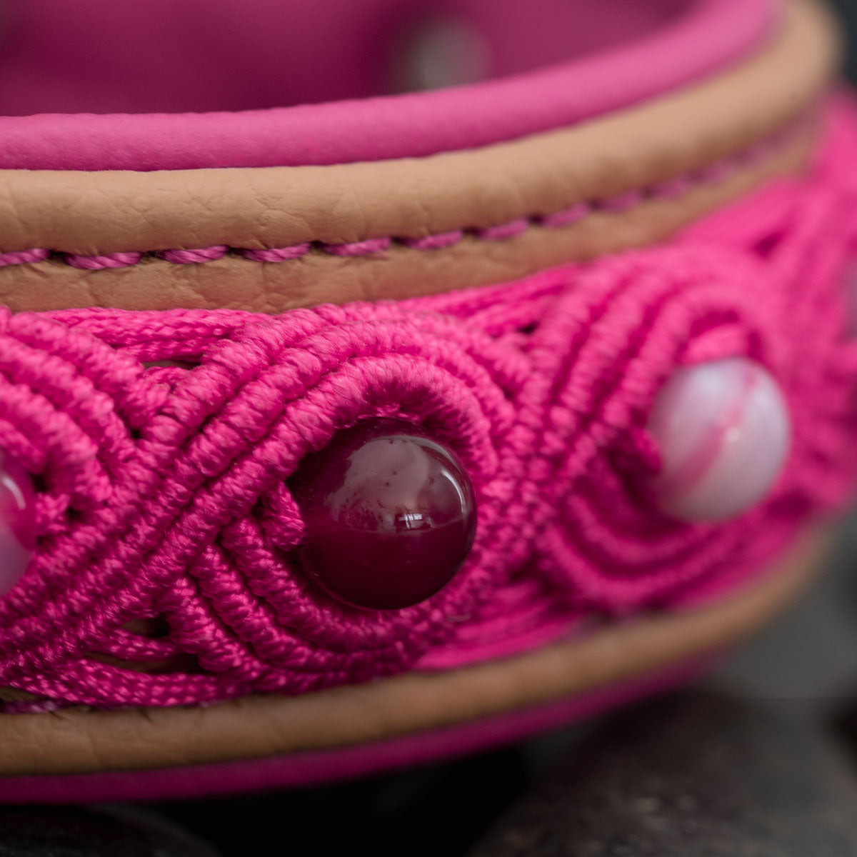 Nahaufnahme von pinken Makramee-Knoten, Streifenachat und pinker Naht am cappuccinofarbenen Leder des Hundehalsbands.