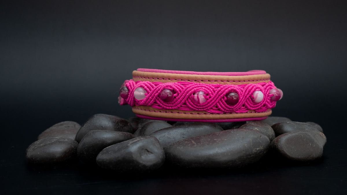 Makramee-Hundehalsband in Cappuccino und Pink mit Streifenachaten, frontal auf dunklen Steinen im Querformat fotografiert.