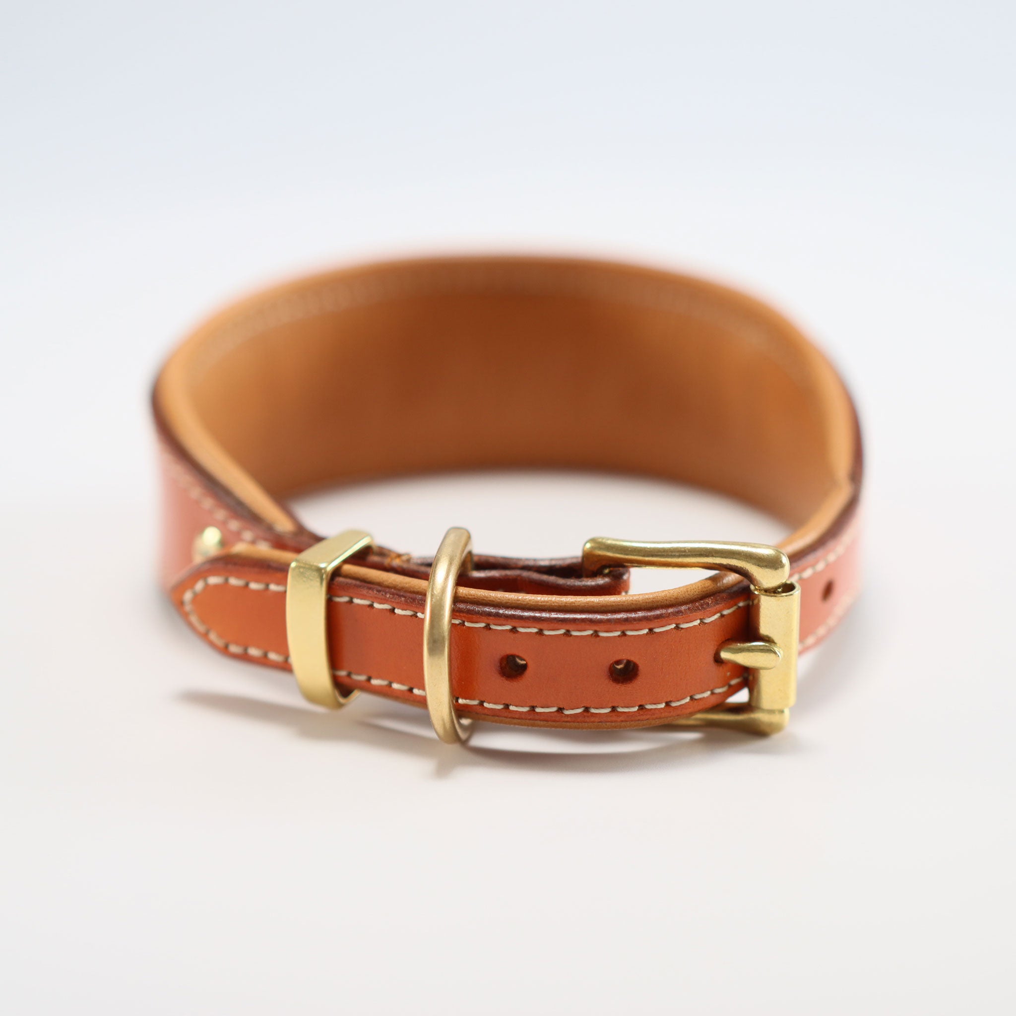 Detailaufnahme der goldenen Messing-Dornschließe am cognacfarbenen Lederriemen