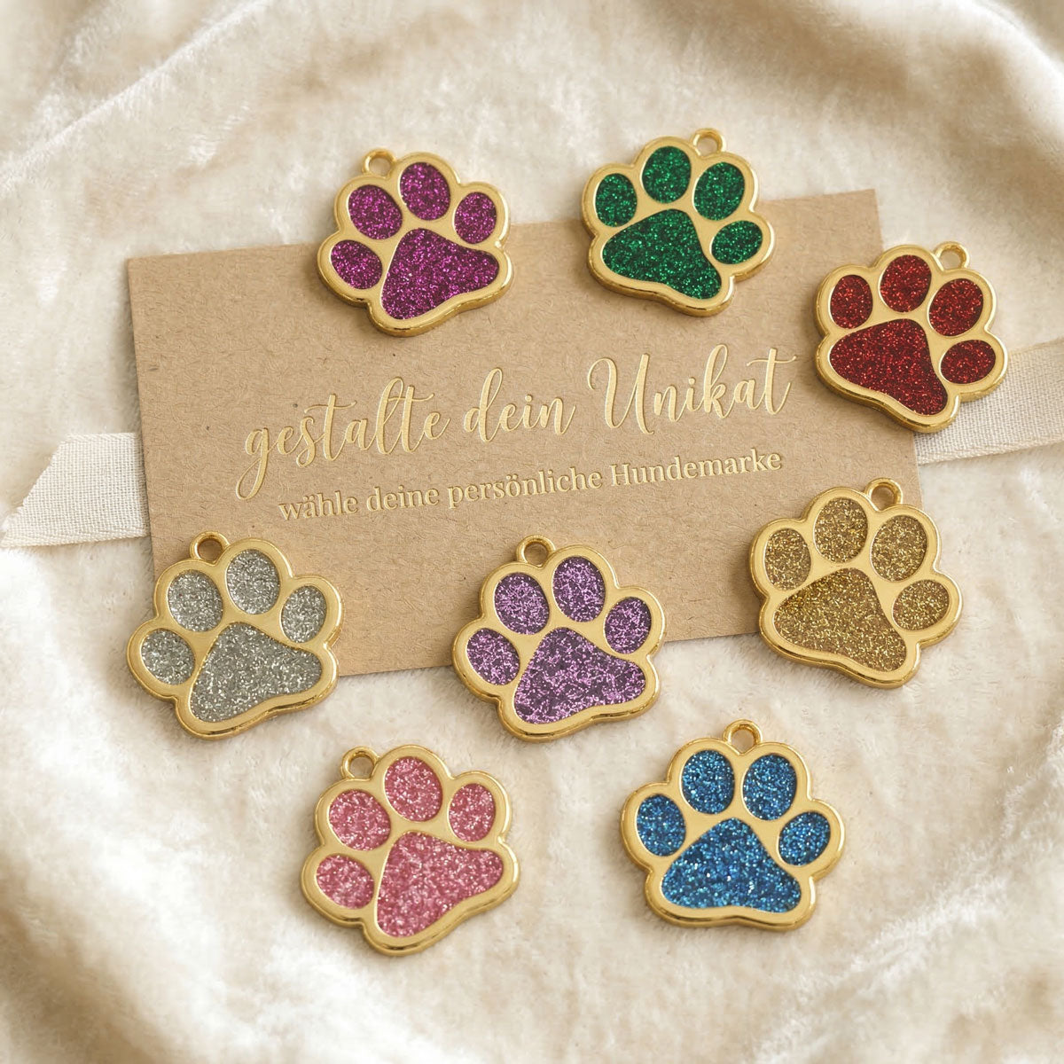 Übersicht verschiedener personalisierbarer Hundemarken in Gold mit bunten Glitzer-Pfoten-Inlays.