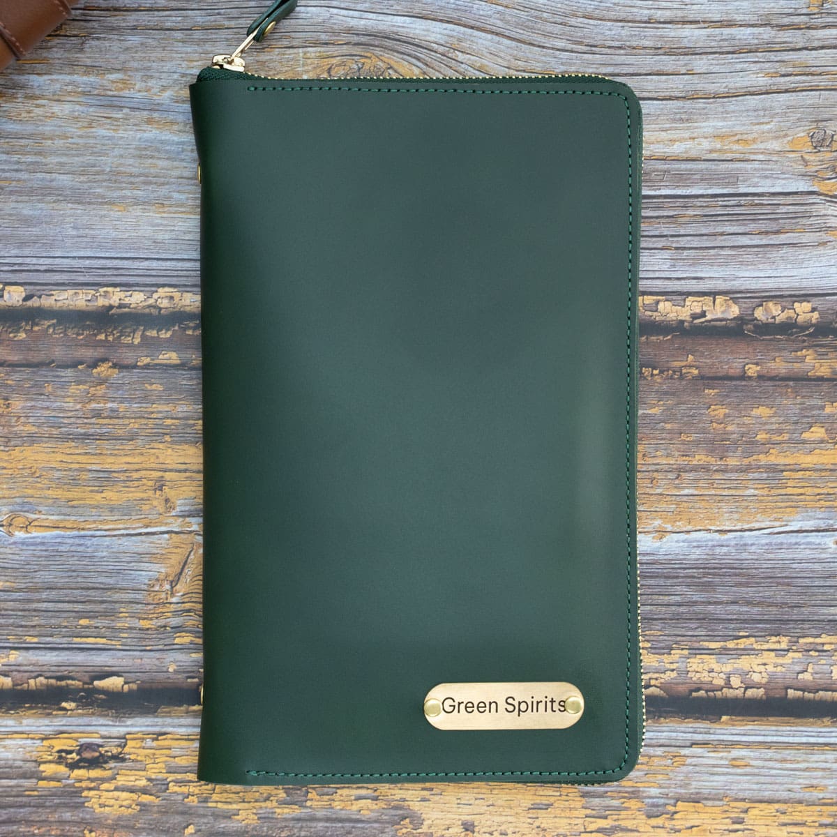 Handgefertigtes Leder Reise-Etui in tiefem Grün. Auf der Vorderseite ist eine mit Messingnieten befestigte Messingplatte angebracht, die das Logo "Green Spirits" als Beispiel für die hochwertige, individuelle Lasergravur zeigt