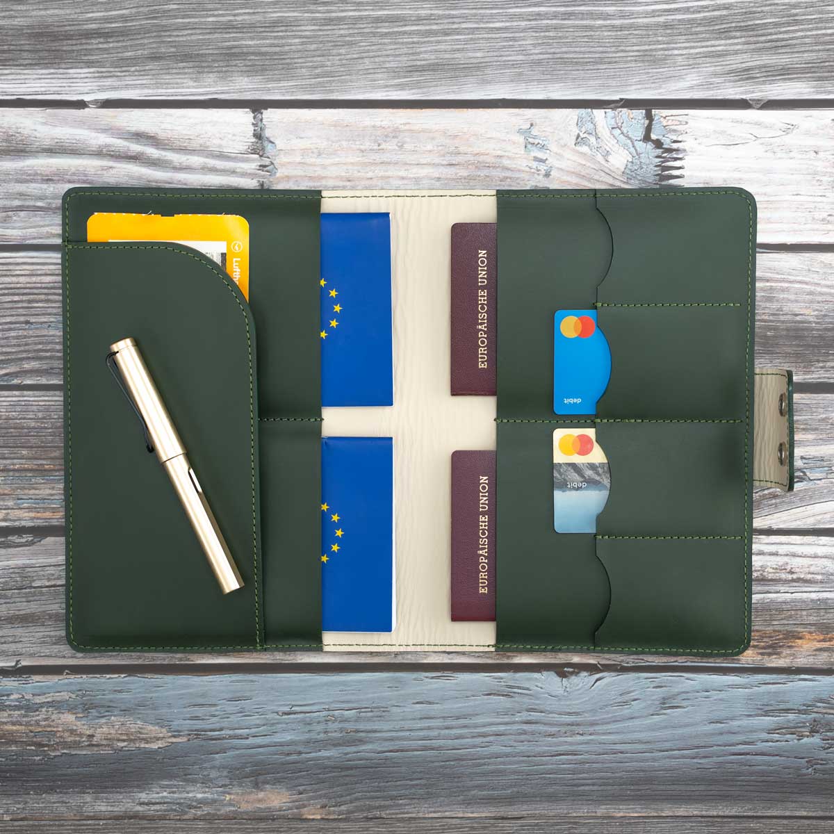 Befülltes dunkelgrünes Travel Wallet. Die praktische Aufteilung zeigt vier sicher verstaute Reisepässe, die alternativ auch durch EU-Heimtierausweise ersetzt werden können, sowie griffbereite Bankkarten und ein Ticket.