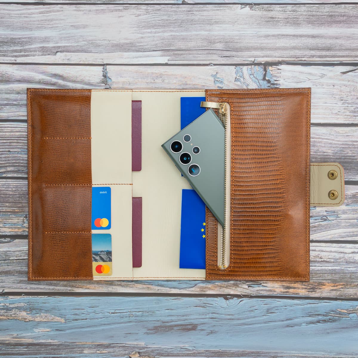 Befülltes Leder-Reise-Etui in Cognac. Praktische Aufteilung mit Platz für Reisepässe, EU-Heimtierausweis, Kreditkarten und ein großes Smartphone im sicheren Reißverschlussfach.