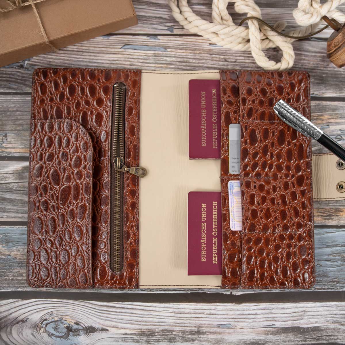 Befülltes Travel Wallet aus whiskey-farbenem Kroko-Leder. Die Innenaufteilung aus hell-taupefarbenem Kalbsleder bietet sicheren Platz für Reisepässe und Karten.