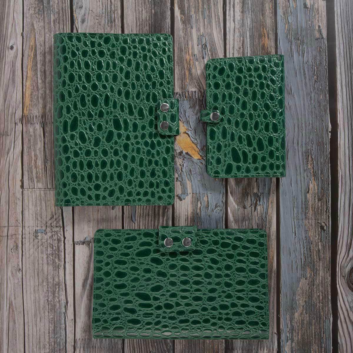 Gesamtansicht des geöffneten und geschlossenen Travel Wallets aus grünem Leder mit Krokodilprägung auf hellem Hintergrund.