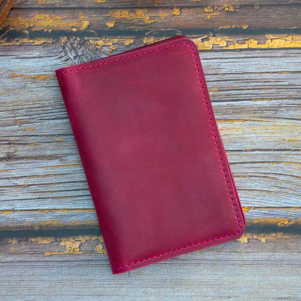 Vorderseite der handgefertigten Leder-Reisepasshülle aus Crazy Horse Leder in der Farbe Wild Berry mit passender Ziernaht.