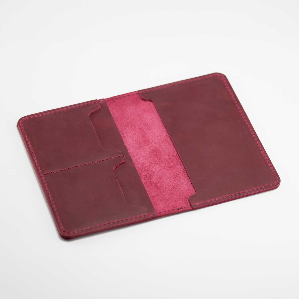 Geöffnete Leder-Reisepasshülle in Wild Berry ohne Inhalt, mit sichtbaren Kartenfächern und bewusst naturbelassenen Innenkanten.