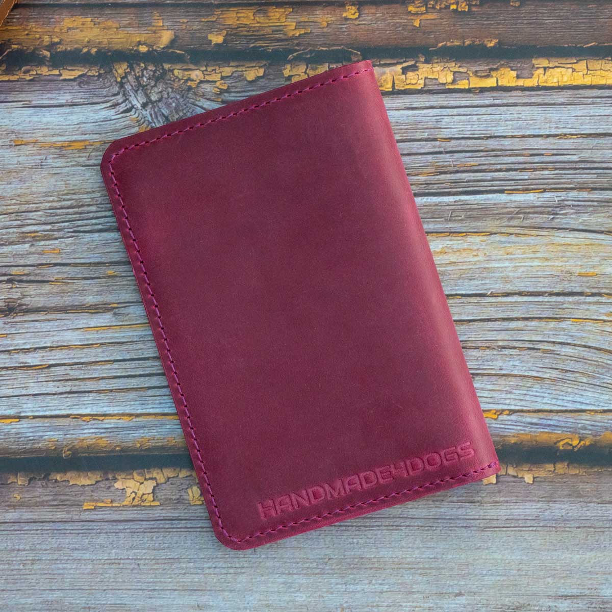 Rückseite der magentafarbenen Leder-Reisepasshülle mit dezent eingeprägtem handmade4dogs Logo am unteren Rand.