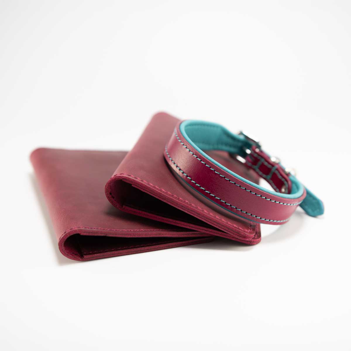 Magentafarbene Leder-Reisepasshülle elegant drapiert neben einem farblich perfekt passenden, handgefertigten Hundehalsband.