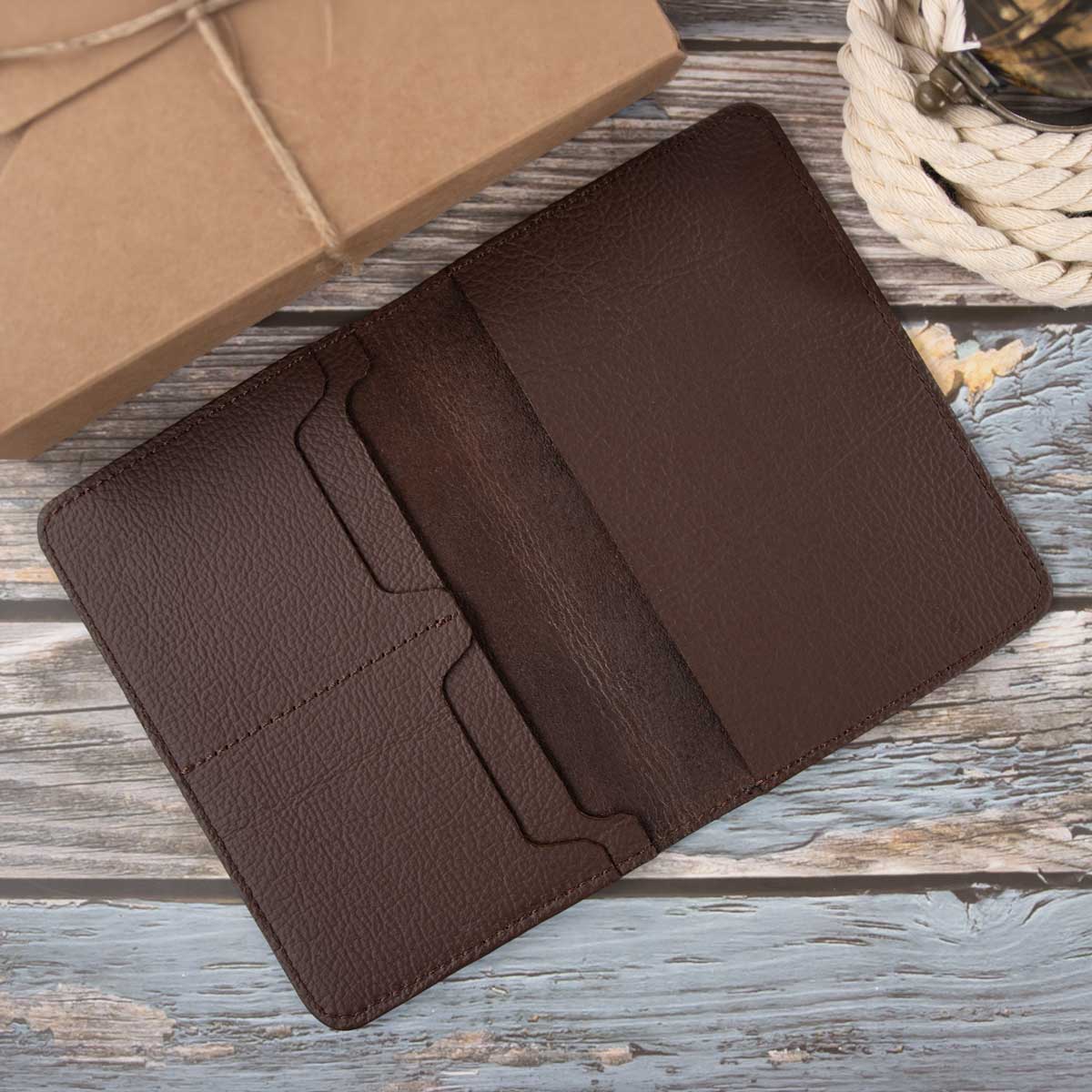 Geöffnete dunkelbraune Leder-Reisepasshülle im minimalistischen Design ohne Innenfutter, mit abgenähten Kartenfächern.