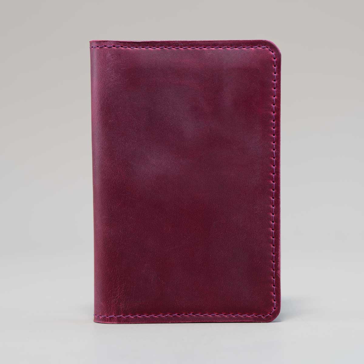 stehende Vorderseite der handgefertigten Leder-Reisepasshülle aus Crazy Horse Leder in der Farbe Wild Berry.